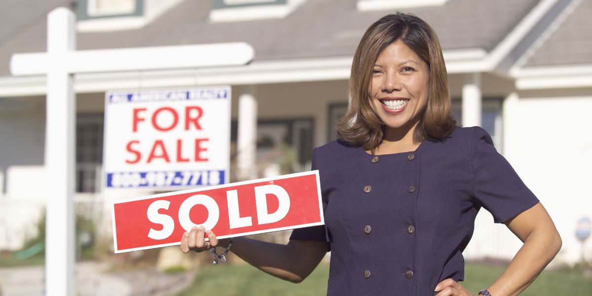 real estate agent holding a "sold" sign